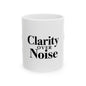 White mug with 'Clarity Over Noise' text on a white background Motivational trading mug next to stock market book on desk with laptop and charts